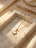 Elegant gold plated necklace with central pearl on green silk
