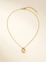 Luxurious lifestyle photography of the golden teardrop necklace on a stone pedestal