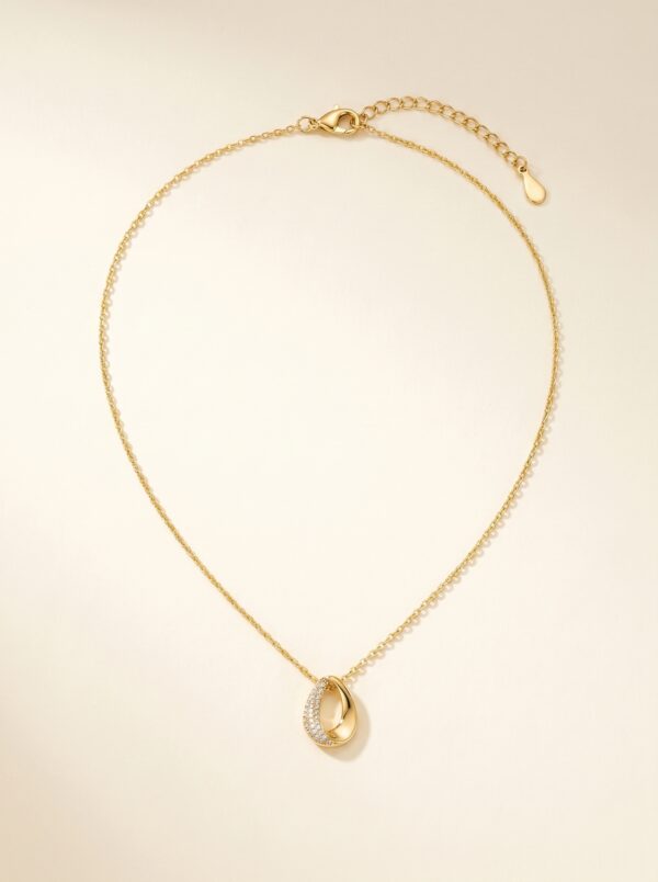 Luxurious lifestyle photography of the golden teardrop necklace on a stone pedestal
