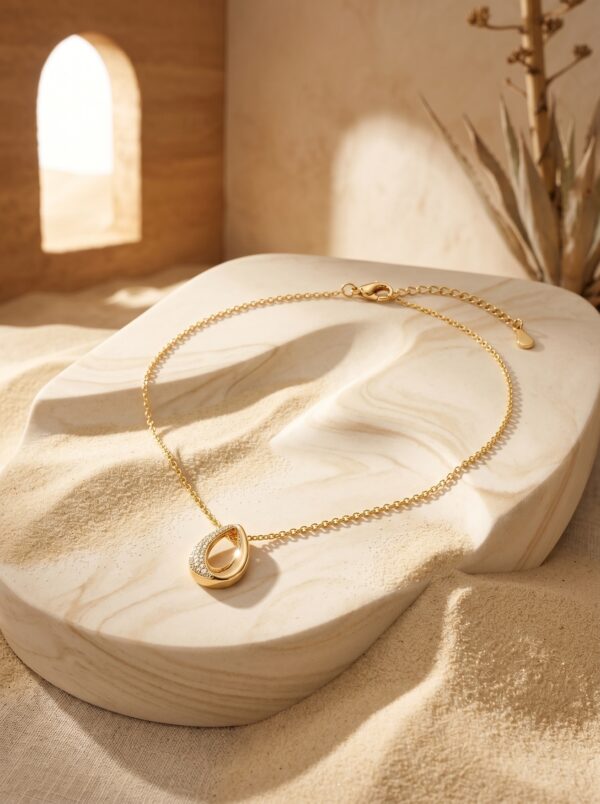 Close up of the Lumina Teardrop Golden Necklace on a white background