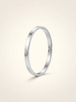 Minimalist silver cuff bracelet resting on stones