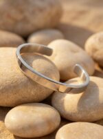 Woman wearing a minimalist silver cuff bracelet holding a coffee cup