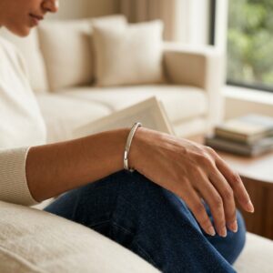 Close up of a sleek silver oval kada resting on a neutral background