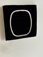 Close up of a sleek silver oval kada resting on a neutral background