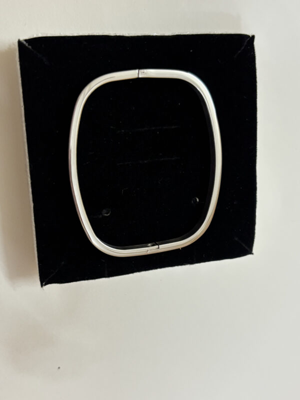 Close up of a sleek silver oval kada resting on a neutral background