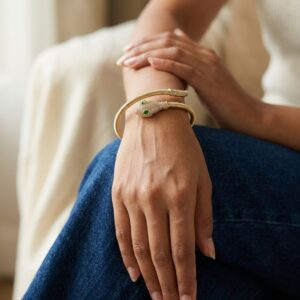 Close up of gold plated coiled snake bracelet with green stones