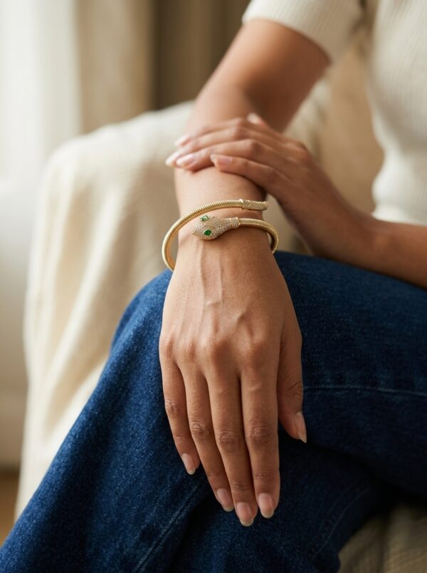 serpentine golden snake kada gal 1 Close up of gold plated coiled snake bracelet with green stones