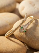 Detailed view of a golden snake bracelet resting on smooth stones