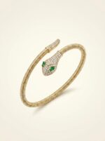 Close up of gold plated coiled snake bracelet with green stones