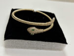 Close up of gold plated coiled snake bracelet with green stones