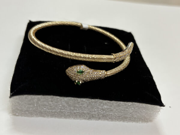 Close up of gold plated coiled snake bracelet with green stones