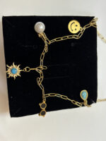 A gold plated necklace resting on a sandy desert surface, highlighting its celestial charms