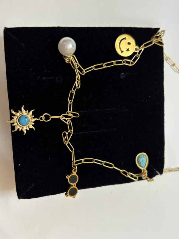 A gold plated necklace resting on a sandy desert surface, highlighting its celestial charms