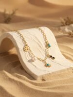 A gold plated necklace with various charms displayed on a black velvet stand
