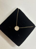 Lifestyle model wearing the gold pendant necklace with a white blouse