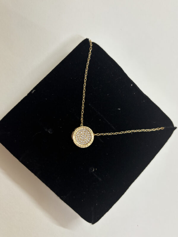 Lifestyle model wearing the gold pendant necklace with a white blouse