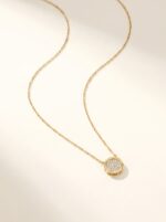 Full shot of the delicate gold chain necklace with a circular paved pendant
