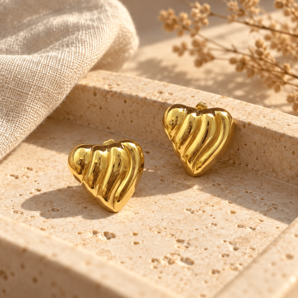 Pair of glossy gold heart earrings isolated on white