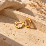 Detailed close-up of a single gold hoop earring showing the hinge mechanism