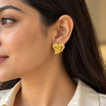 A model wearing elegant gold plated heart earrings with a soft, minimalist aesthetic