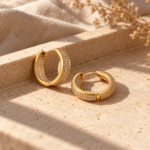 Pair of gold pavé hoop earrings on white background