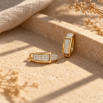 A pair of gold plated huggie hoops on white background