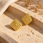 A pair of gold textured stud earrings on a plain white background