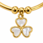 Close up of mother of pearl heart charm on gold bangle