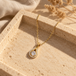 Close-up detail of gold teardrop pendant with clear stone