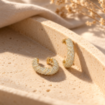 Pair of gold pavé twist hoop earrings on white background