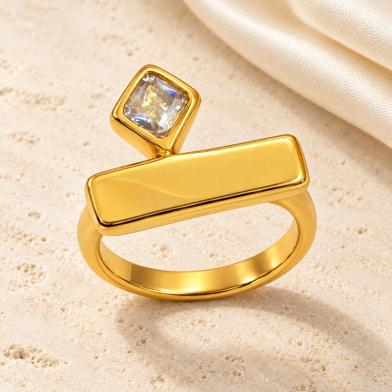 Gold-tone geometric bar ring with a square clear stone on ivory stone and silk